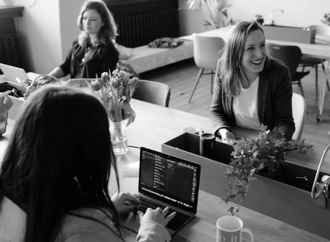 three people sitting at a desk with a computer